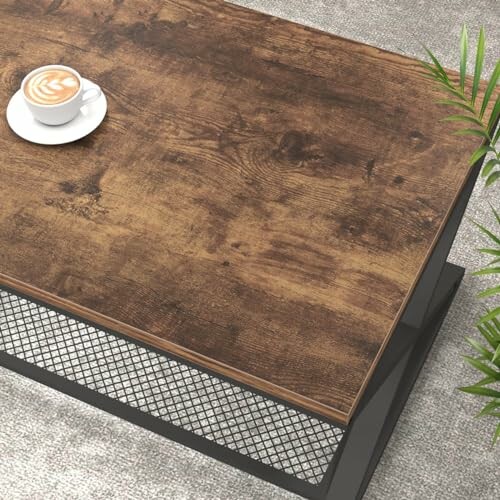 Wooden coffee table with a latte on top and plants nearby.